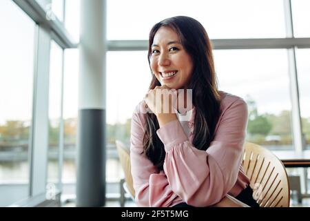 Selbstbewusste Geschäftsfrau mit Hand auf Kinn und Blick auf die Kamera. Weibliche professionelle sitzen im Büro. Stockfoto