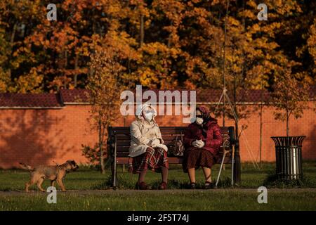 MOSKAU, RUSSLAND - 27 2020. SEPTEMBER: Maskierte Großmütter sitzen im herbstlichen Bitsa-Park auf einer Bank Stockfoto