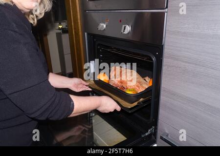 Braten Sie Gans gefüllt mit gebackenen Äpfeln und Orangen in einer Pfanne, die in einem Ofen geschoben wird, festliche Weihnachtsrezept. Draufsicht mit Kopierbereich. Stockfoto