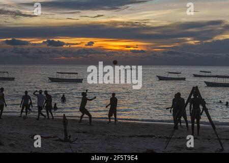 23. März 2020 - Nungwi, Tansania: Silhouetten von dunkelhäutigen Jungs, die am Abend am Strand Ball spielen Stockfoto