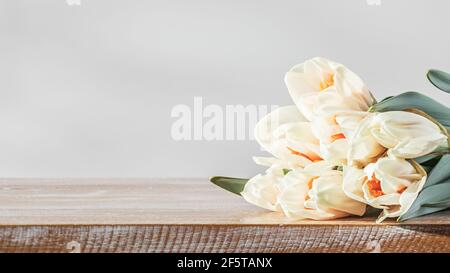 Die Blumen der frühlingshaften Narzissen aus der Nähe auf einem hölzernen Hintergrund bei morgendlichem Sonnenlicht Stockfoto