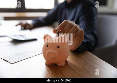 Nahaufnahme Frau, die Münze in rosa Sparschwein Stockfoto