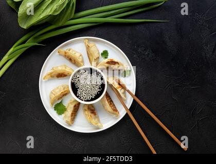 Gebratene Knödel Gyoza mit Sojasauce, und Essstäbchen, Draufsicht. Stockfoto