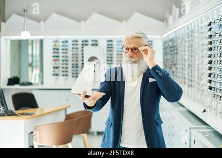 Fokussierter tätowierte Chefkoch in Schürze, der rote Zwiebeln mit Messer hackt, während er in einer hellen Küche kocht Stockfoto