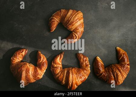 Draufsicht Komposition mit appetitlich frisch gebackenen knusprigen Croissants serviert Dunkler Hintergrund Stockfoto