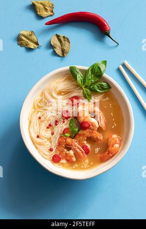 Tom Yum Suppe in Schüssel mit Essstäbchen auf blauem Hintergrund Stockfoto