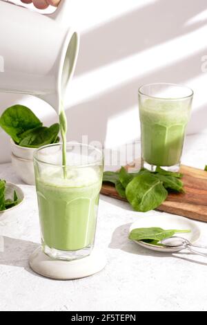 Unkenntlich Person Gießen gesunden Spinat Smoothie in Glas platziert auf Tisch für Frühstück zu Hause Stockfoto