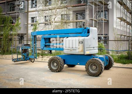 Blaue Arbeitsbühne auf dem Hintergrund des Gebäudes. Mobilkran auf der Baustelle. Auslegerlift im Freien. Teleskop-Aufzug zu vermieten Stockfoto