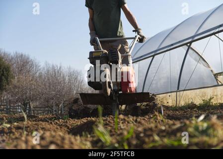 Ein Bauer bereitet mit einem Cutter den Boden für den Sommergarten vor. Hochwertige Fotos Stockfoto
