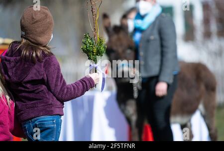 Tutzing, Deutschland. März 2021, 28th. Ein Mädchen mit einem sogenannten 'Palmstrauß' nimmt am Palmsonntag vor der St. Josephskirche Teil. Palmsonntag markiert den Beginn der vorösterlichen Karwoche mit Ostern als Höhepunkt des Kirchenjahres. Quelle: Sven Hoppe/dpa/Alamy Live News Stockfoto