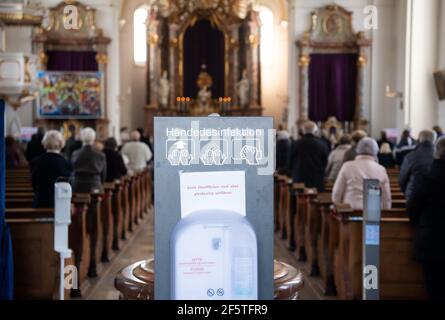 Tutzing, Deutschland. März 2021, 28th. Gemeindemitglieder nehmen an den Gottesdiensten am Palmsonntag in der St. Joseph Kirche Teil. Im Vordergrund ist ein Dispenser von Desinfektionsmittel. Der Palmsonntag markiert den Beginn der vorösterlichen Karwoche mit Ostern als Höhepunkt des Kirchenjahres. Quelle: Sven Hoppe/dpa/Alamy Live News Stockfoto