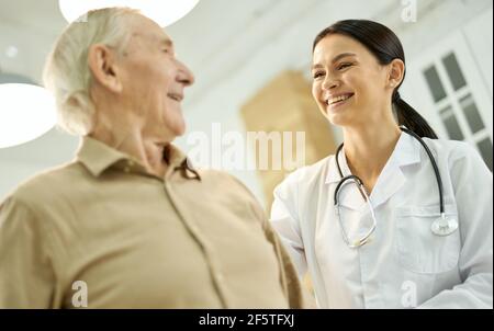 Ausscheidende medizinische Mitarbeiterin, die sich um ihre ältere Patientin kümmert Stockfoto