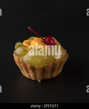 Fruit Dessert Kuchen mit Kirschtrauben, Kiwi und Zitrusfrüchten, auf schwarzem Hintergrund isoliert Stockfoto