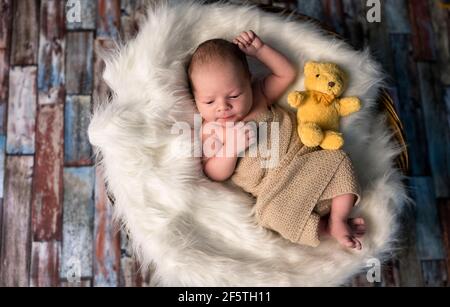 Kleines neugeborenes Baby in einem gestrickten Teppich in der Nähe von Teddy verzogen Bären Spielzeug Stockfoto