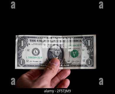 Hand hält 1 Dollar über schwarzem Hintergrund Stockfoto