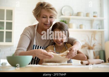 Fürsorgliche Großmutter Backen Kuchen mit kleinen 9s Enkelin Stockfoto