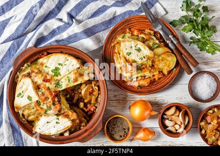 Tartiflette, French Potato, Bacon und Käse Auflauf in einer Tonplatte und eine Portion auf einem Teller, französische Küche Stockfoto