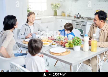 Essen und genießen. Glückliche lateinische Familie genießen zusammen Essen, sitzen am Tisch in der Küche zu Hause Stockfoto