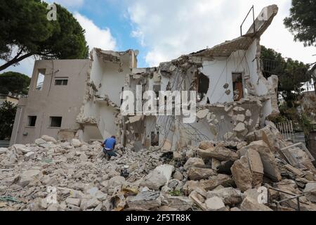 Mann kniet vor dem zerbrochenen Haus auf Ruine Abriss Ort nach der Zerstörung. Stockfoto