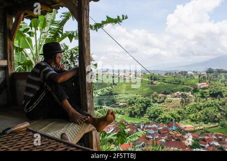 Abah Udi macht nach dem Trocknen von Tabak in Sumedang eine Pause. Banyuresmi Village, Sumedang Regency ist nach Garut als das zweitgrößte Tabakanbaugebiet in West-Java bekannt. Die Mehrheit der Einwohner dieses Dorfes wählt, als Tabakbauern zu arbeiten, die von Generation zu Generation praktiziert wurden. Wenn wir dieses Dorf besuchen, werden wir sehen, wie weite Flächen des Tabaktrocknungsprozesses unter der Sonne die Dorfstraßen, Dächer, Terrassen des Hauses füllen. Dieses Dorf ist in der Lage, die Marktnachfrage aus allen indonesischen Provinzen einschließlich West Java, Bali und Sumatra zu erfüllen. Einige von ihnen wurden sogar ins Ausland exportiert, Stockfoto