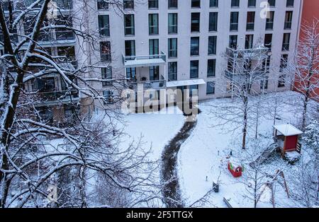 Verschneite Kinderspielecke im Garten des Mehrfamilienhauses, Mitte, Berlin, Deutschland Stockfoto