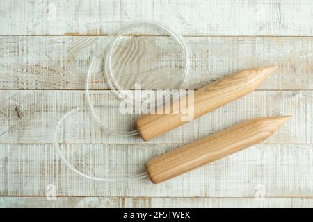 Dicke Holzstricknadeln zum Stricken großer Gegenstände mit Merino Wolle auf einem Holzboden Stockfoto