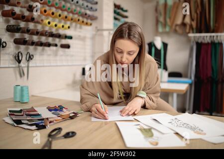 Frau Modedesignerin zeichnet Skizzen. Attraktive junge Schneiderin skizzieren im Studio Stockfoto
