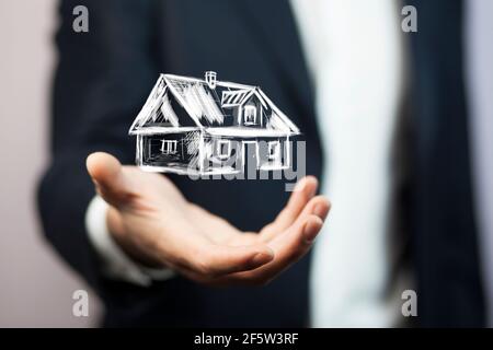 Immobilienangebot. Geschäftsmann hält ein künstliches Modell des Hauses Stockfoto