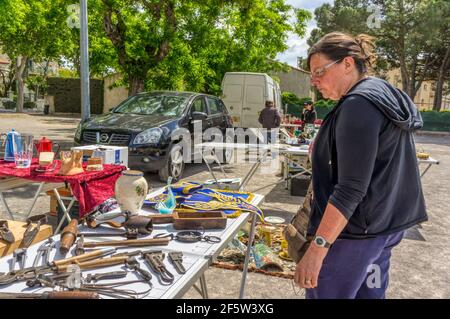 Frau im Urlaub bei der Suche nach Artikeln zum Verkauf auf einem Flohmarkt in der südfranzösischen Stadt Marseillan. Stockfoto