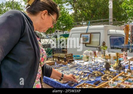 Frau im Urlaub bei der Suche nach Artikeln zum Verkauf auf einem Flohmarkt in der südfranzösischen Stadt Marseillan. Stockfoto