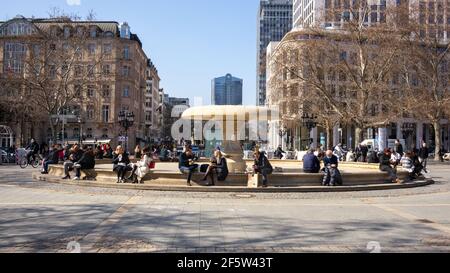 Die Leute sitzen draußen an der Brunnengrenze mit Abstand, mit Essen zum Mitnehmen in der Mittagspause, im Finanzzentrum, während die Restaurants geschlossen bleiben. Stockfoto