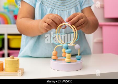Nahaufnahme der Hände eines kaukasischen zweijährigen Mädchens, das mit montessori Lernspielzeug spielt. Stockfoto