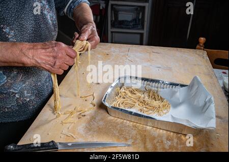 Oma arrangiert Eiernudeln auf der Aluminiumsohle Stockfoto