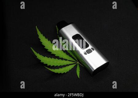 Elektronischer Verdampfer mit Cannabisblatt auf schwarzem Hintergrund Stockfoto