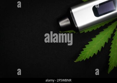 Elektronischer Verdampfer mit Cannabisblatt auf schwarzem Hintergrund Stockfoto