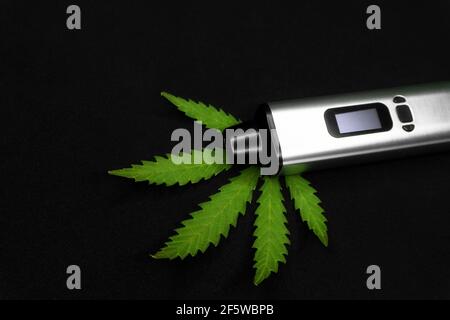 Elektronischer Verdampfer mit Cannabisblatt auf schwarzem Hintergrund Stockfoto