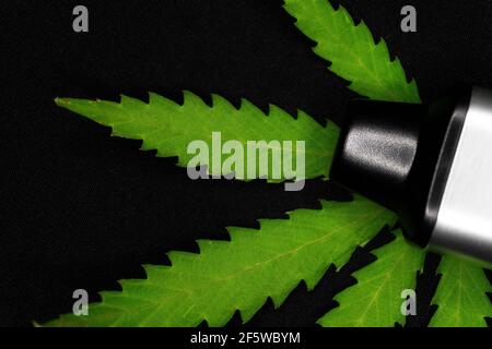 Elektronischer Verdampfer mit Cannabisblatt auf schwarzem Hintergrund Stockfoto