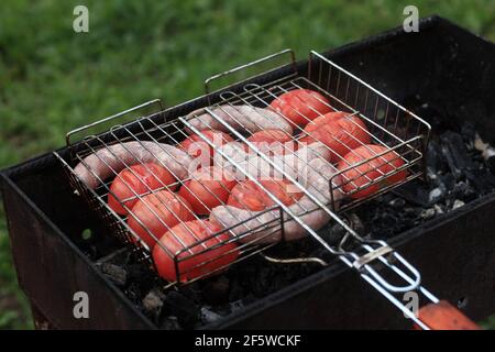 Würste mit Tomaten auf dem Grill kochen Stockfoto