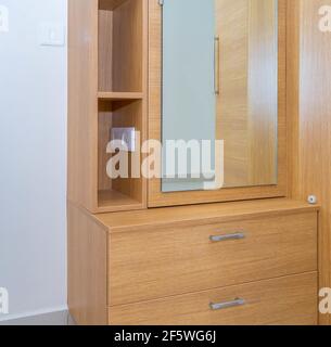 Eine vertikale Aufnahme eines Schlafzimmerschranks mit Spiegel Und einer Steckdose Stockfoto