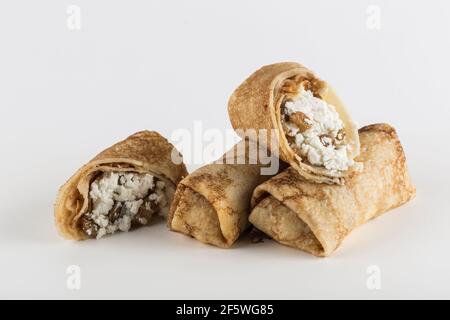 Mehrere Pfannkuchen gefüllt mit Hüttenkäse mit Rosinen auf weißem Hintergrund Nahaufnahme mit einer Kopie Platz für den Text, isoliert. Traditionelles Essen Stockfoto