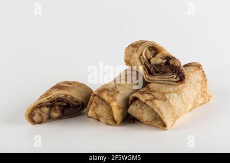 Mehrere Pfannkuchen mit Bananenfüllung mit Schokolade auf weißem Hintergrund Nahaufnahme mit einem Kopierplatz für den Text, isoliert. Traditionelles Essen für die Stockfoto