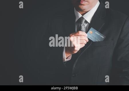 Geschäftsleute nehmen die Kreditkarte aus der Tasche Anzug auf schwarzem Hintergrund, Geld Zahlungskonzept Stockfoto