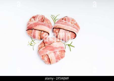 Drei Hamburger mit Speck auf einem weißen Teller mit einem Zweig Rosmarin. Leckeres Essen, Fast Food zu Hause. Roher HähnchenHamburger mit Vollhäuter. Stockfoto