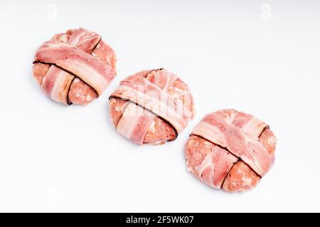 Speicherplatz kopieren. Nahaufnahme von drei Hamburgern mit Speck auf einem weißen Teller mit einem Zweig Rosmarin und schwarzem Pfeffer. Leckeres Essen, Fast Food zu Hause. Raw, Stockfoto