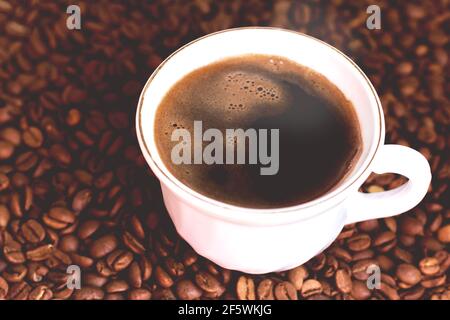Eine Tasse frisch gebrühten Kaffees auf gerösteten Kaffeebohnen. Stockfoto
