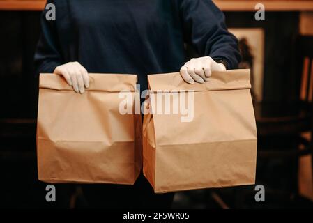 Essen zum Mitnehmen Konzept. Mädchen hält Papptaschen mit Essen vor der Kamera Stockfoto