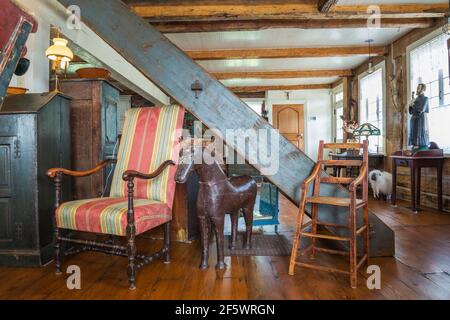 Rot, aqua-blau und gelb gestreiften gepolsterten Sessel aus antikem Holz, Hochstuhl mit Sitz aus massivem Holz, Holzpferdeskulptur im Wohnzimmer Stockfoto
