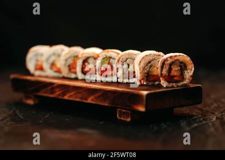 Nahaufnahme von Sushi mit Lachs und Avocado auf einem hölzernen Schneidebrett Stockfoto