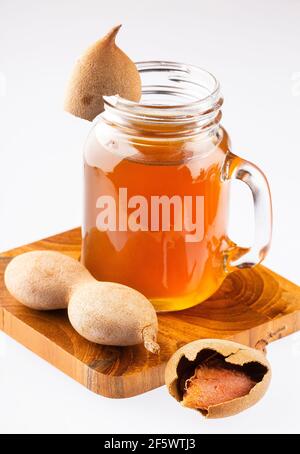 Tamarindensaft in einem Glas, umgeben von frischen reifen Tamarinden Stockfoto