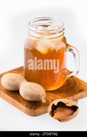 Tamarindensaft in einem Glas, umgeben von frischen reifen Tamarinden - Tamarindus indica Stockfoto
